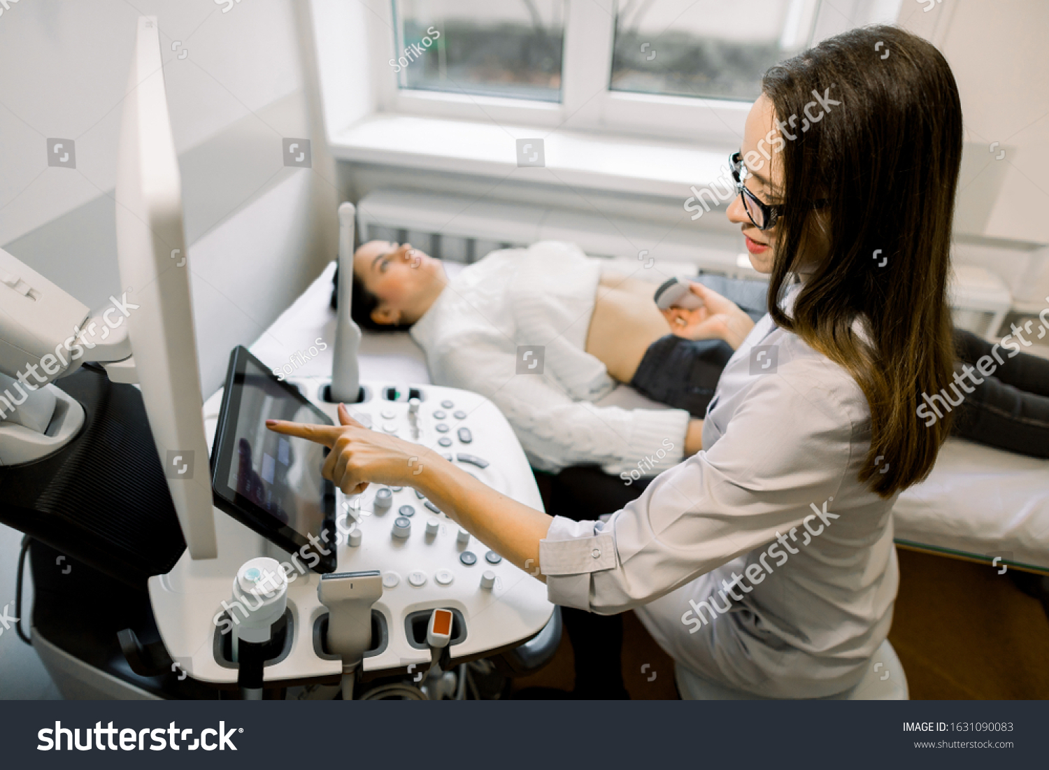 stock-photo-young-woman-doctor-preparing-to-the-abdominal-ultrasound-for-female-patient-doctor-pushes-buttons-1631090083